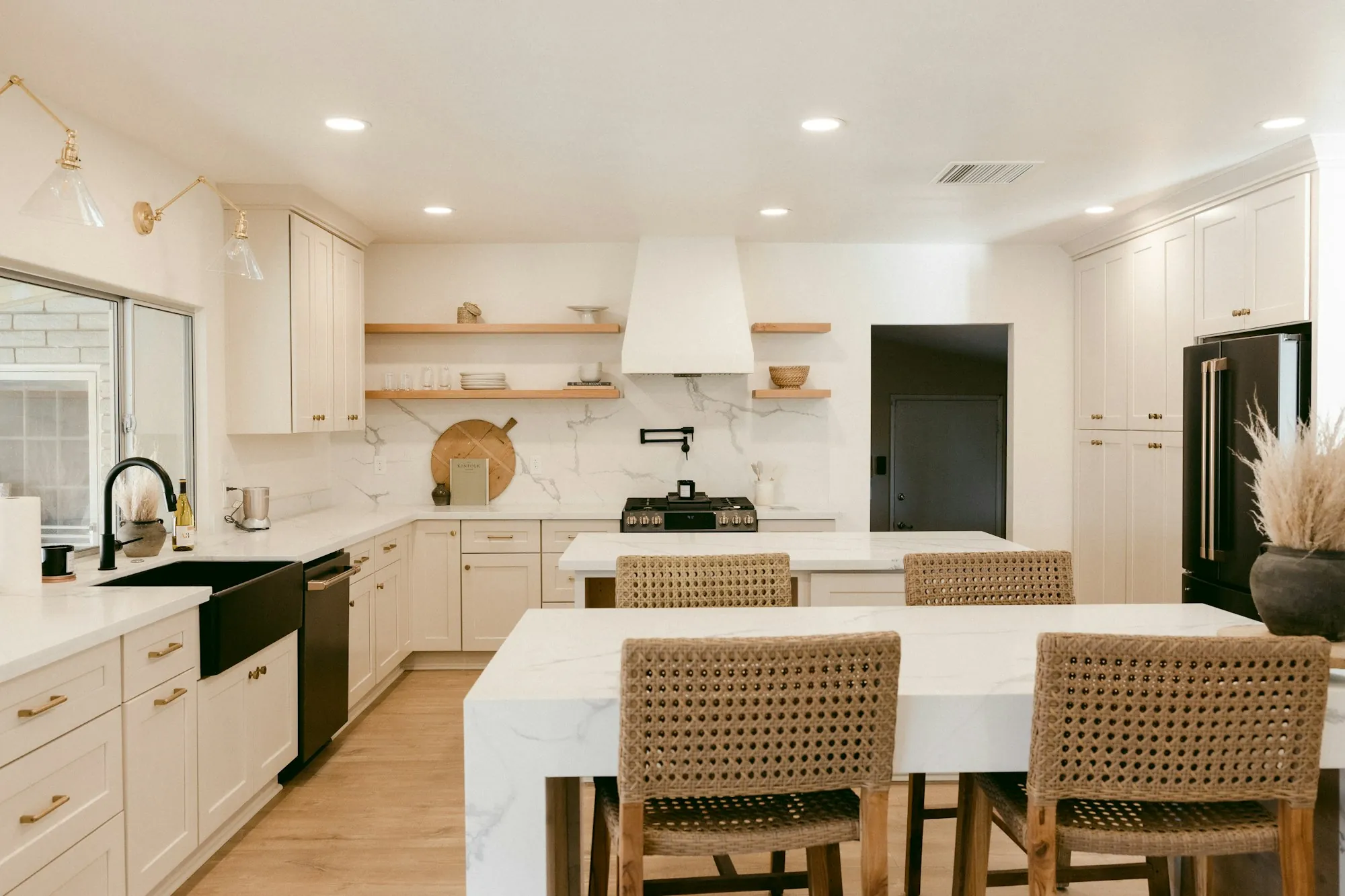 Bright white kitchen with an island, stools and recessed ceiling lights