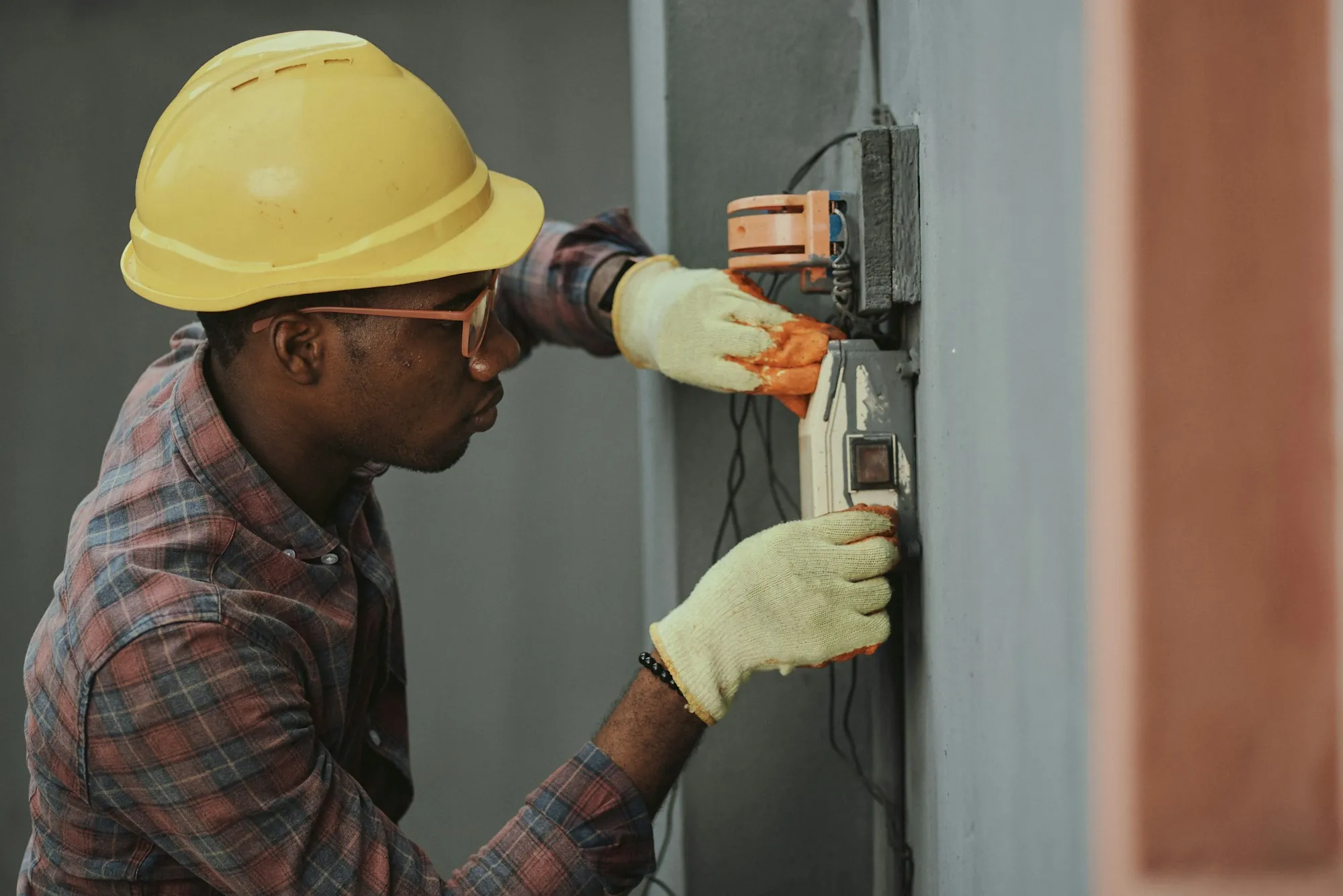 Electrician in a hard hat working inside a residential electrical panel