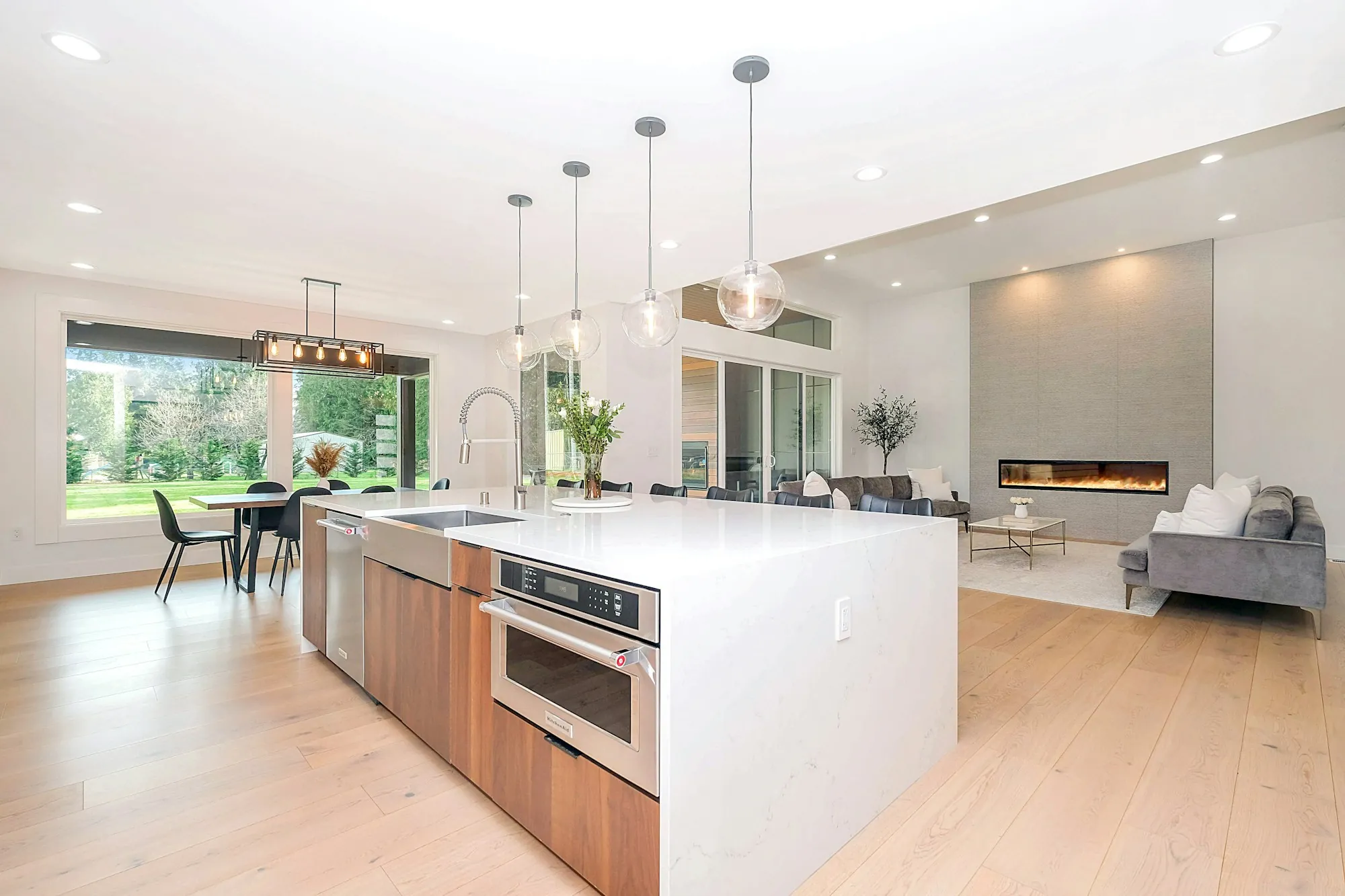 Long kitchen island with pendant lights and a bright open living area