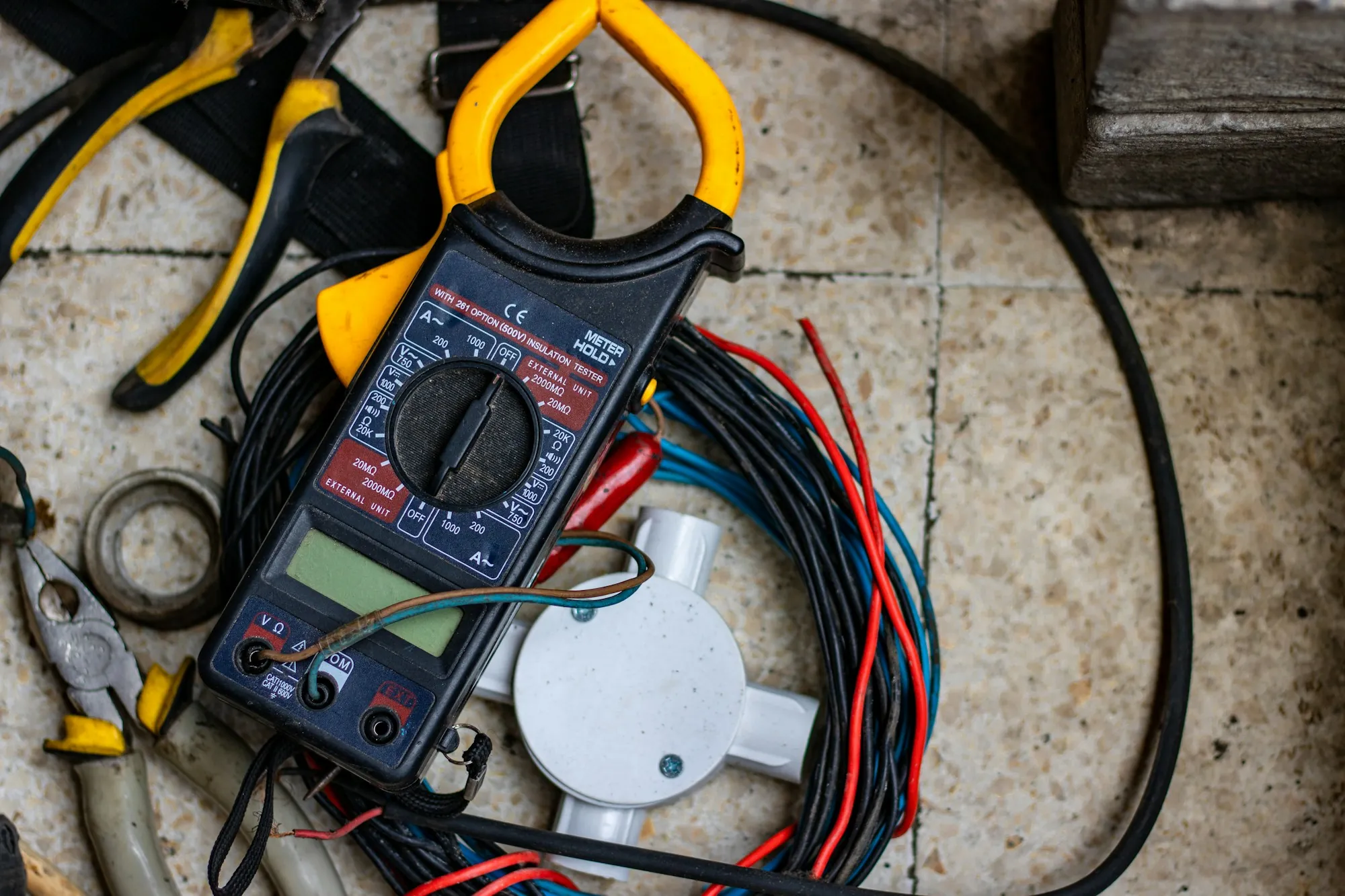 Multimeter and test leads next to a coil of electrical wire