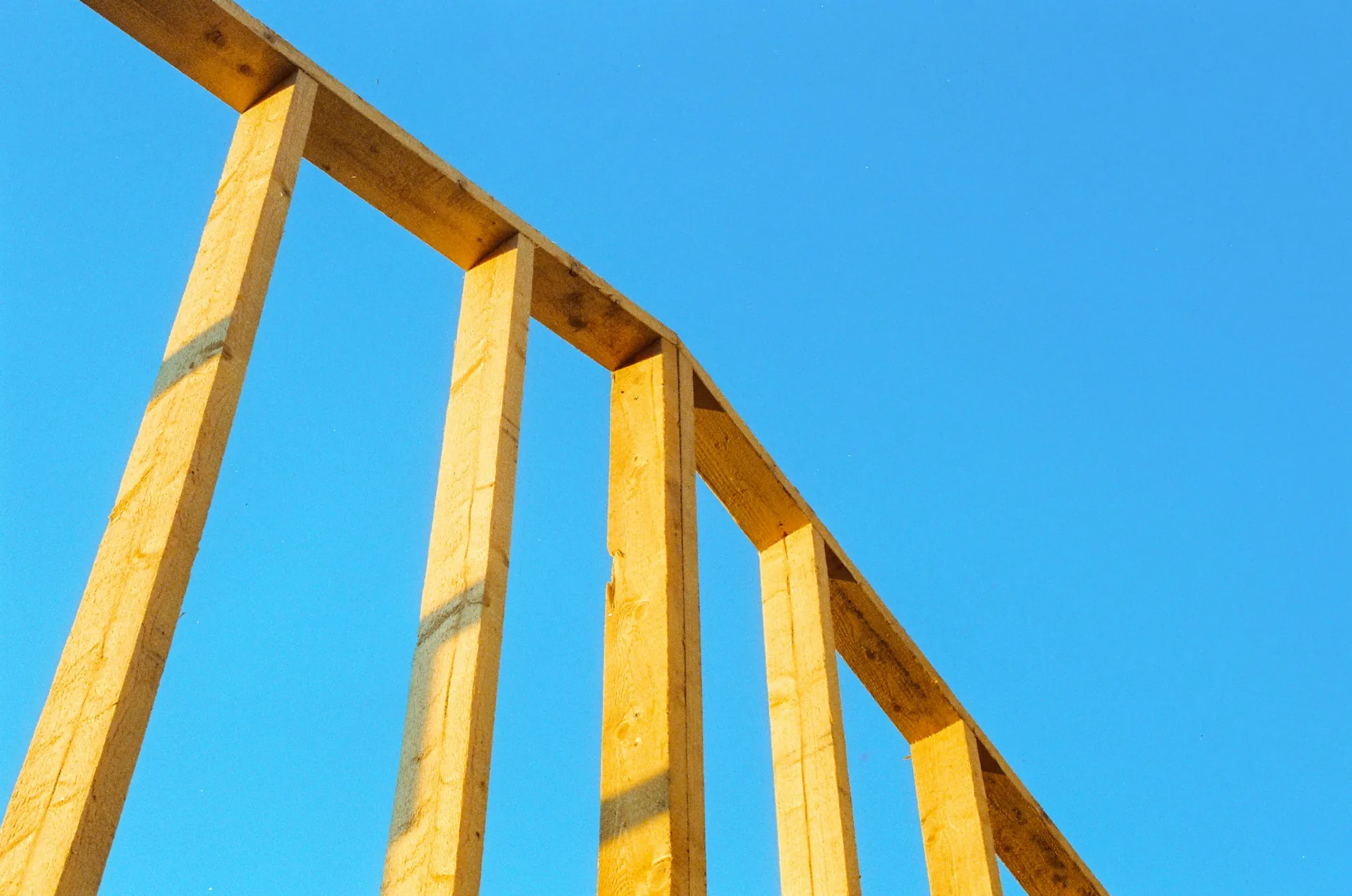 Wooden wall framing against a clear blue sky